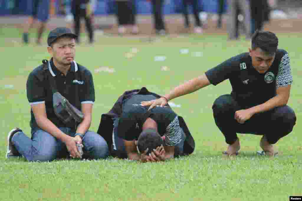 Arema FC players and officials react as they visit Kanjuruhan Stadium, after a riot and stampede following a soccer match between Arema vs Persebaya in Malang, East Java province, Indonesia. (Antara Foto. Antara Foto/Prasetia Fauzani/via Reuters)