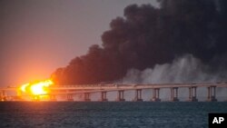 Flame and smoke rise from Crimean Bridge connecting Russian mainland and Crimean Peninsula over the Kerch Strait, Oct. 8, 2022.