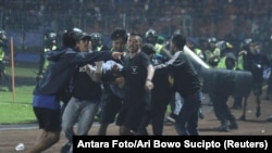 Sejumlah suporter berupaya mengevakuasi seorang pria yang terkena tembakan gas air mata setelah kisruh meletus selepas pertandingan antara Arema melawan Persebaya di stadion Kanjuruhan, Malang, pada 1 Oktober 2022. (Foto: Antara Foto/Ari Bowo Sucipto/via Reuters)
