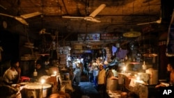 Vendors light candles at a market after a failure in Bangladesh's national power grid plunged much of the country into a blackout in Dhaka, Bangladesh, Oct.4, 2022.
