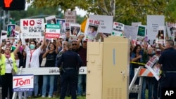 People hold signs showing their support for Iranian protesters standing up to their leadership over the death of Mahsa Amini in police custody, as the motorcade for President Joe Biden arrives at Irvine Valley Community College, in Irvine, Calif., Oct. 14, 2022.
