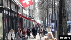 FILE - Shoppers walk along the Bahnhofstrasse shopping street in Zurich, Switzerland, March 1, 2021. 