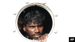 A Sri Lankan asylum seeker who was rescued from a troubled boat adrift trying to reach Australia looks out from a porthole of a rescue ship upon arrival at Teluk Bayur port in Padang, West Sumatra, Indonesia, January 2, 2013. 