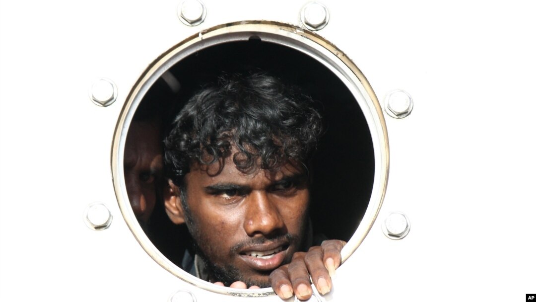 Seorang pencari suaka dari Sri Lanka yang diselamatkan dari kapal menuju Australia mengintip dari kapal penyelamat di pelabuhan Teluk Bayur, Padang. (Foto: Dok)