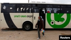 FILE - Laborers disembark a Palestinians-only bus before crossing through Israel's Eyal checkpoint as they returns to the West Bank, near Qalqilya.