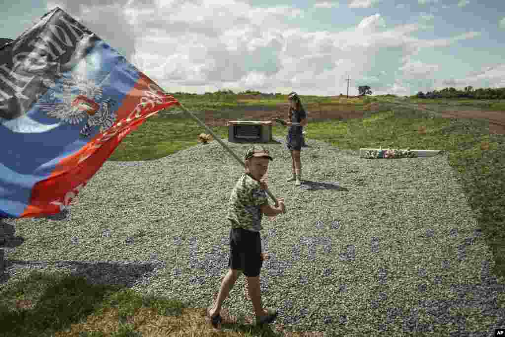 Um rapaz anda com uma bandeira da auto-proclamada República do Povo de Donetsk numa homenagem às vítimas da queda do avião da Malaysian Airlines MH17, no lugar junto à queda do aparelho, a vila de Hrabove, leste da Ucrânia, Julho 16, 2015.