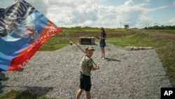 A boy waves a flag of the self-proclaimed Donetsk People's Republic at a memorial to the victims of the Malaysian Airlines MH17 plane crash at the crash site near the village of Hrabove, eastern Ukraine, July 16, 2015.