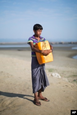 Rohingya Muslim Nabi Hussain, 13, poses for a portrait with the yellow plastic drum he used as a flotation device to cross the Naf River in Shar Porir Dwip, south Cox's Bazar, Bangladesh, Nov. 4, 2017. He clung to the empty drum and struggled across the water for 2.5 miles.