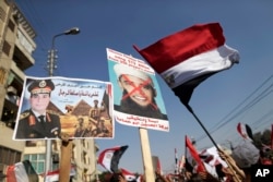 FILE - In this July 26, 2013, photo opponents of Egypt's ousted President Mohammed Morsi wave Egyptian flags and hold a poster depicting then general, Abdel-Fattah el-Sissi, while another holds an modified image of then President Barack Obama, showing him