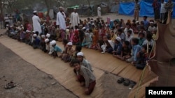 FILE - People from the Burmese Rohingya Community from Myanmar, sit in an open air madrasa, or a religious school, at a camp in New Delhi May 14, 2012.