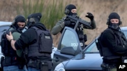 Police officers prepare for an operation near a road where two police officers were shot dead during a traffic stop near Kusel, in western Germany, Jan. 31, 2022. 