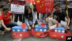 FILE - Filipino student activists set fire mock Chinese ships to protest recent island-building and alleged militarization by China off the disputed Spratlys group of islands in the South China Sea, in Manila, March 3, 2016. 