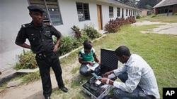 A police officer provides security as Electoral Officials check voter registration material and election equipment at a distribution center in Lagos, Nigeria, 15 Jan, 2011