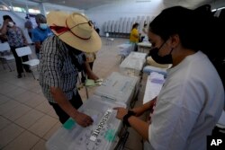 Yon neg depoze bilten ni nan yon biwo'd vot pandan eleksyon prezidansyel la nan vil Santiago, Chili, Dimanch 21 Nov. 2021.