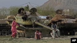 FILE - Afghan boys play on the remains of an old Soviet tank on the outskirts of Kandahar, south of Kabul, Afghanistan, Feb. 21, 2015.