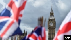 FILE - National flags flutter near the The Elizabeth Tower, commonly referred to as Big Ben, in central London, June 9, 2017. 