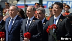 Russian President Vladimir Putin (C), Kazakhstan's President Nursultan Nazarbayev (L) and China's President Xi Jinping take part in a wreath laying ceremony at the Tomb of the Unknown Soldier on the Victory Day by the Kremlin walls in central Moscow, Russ