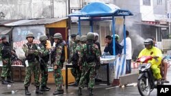 Soldiers stand guard along a road after Sunday's riots in Ambon September 12, 2011. Several people were killed and dozens injured when riots broke out on Sunday after rumors spread online that a motor taxi driver was tortured to death by a group of reside
