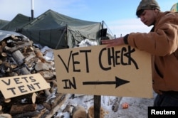 A man makes a sign that reads "vet check in" in Oceti Sakowin camp as "water protectors" continue to demonstrate against the Dakota Access pipeline near the Standing Rock Indian Reservation, Cannon Ball, N.D., Dec. 3, 2016.