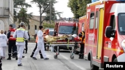 Rescue workers carry a injured person on a stretcher during rescue operations near the site where a coach carrying members of an elderly people's club collided with a truck outside Puisseguin near Bordeaux, western France, October 23, 2015.