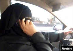 FILE - Umm Ibrahim sits behind the wheel of her vehicle as she drives in Riyadh, an act that is banned in Saudi Arabia.