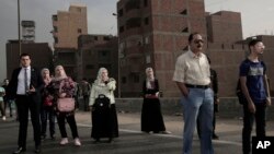 In this Oct. 23, 2018 photo, people wait for an early morning bus on the ring road, in Cairo, Egypt. (AP Photo/Nariman El-Mofty)