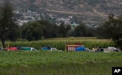 FILE - Gasoline thieves wait in line to steal gas from an illegal tap into a state-owned pipeline, in the middle of a cornfield in San Bartolome Hueyapan, Tepeaca, Mexico, July 11, 2017.