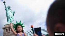 Una niña posa frente a la Estatua de la Libertad en la reapertura del tradicional monumento este 4 de julio en la Isla de la Libertad en Nueva York. La Estatua de la Libertad no fue dañada con el paso del huracán Sandy, pero sí el muelle de la isla.