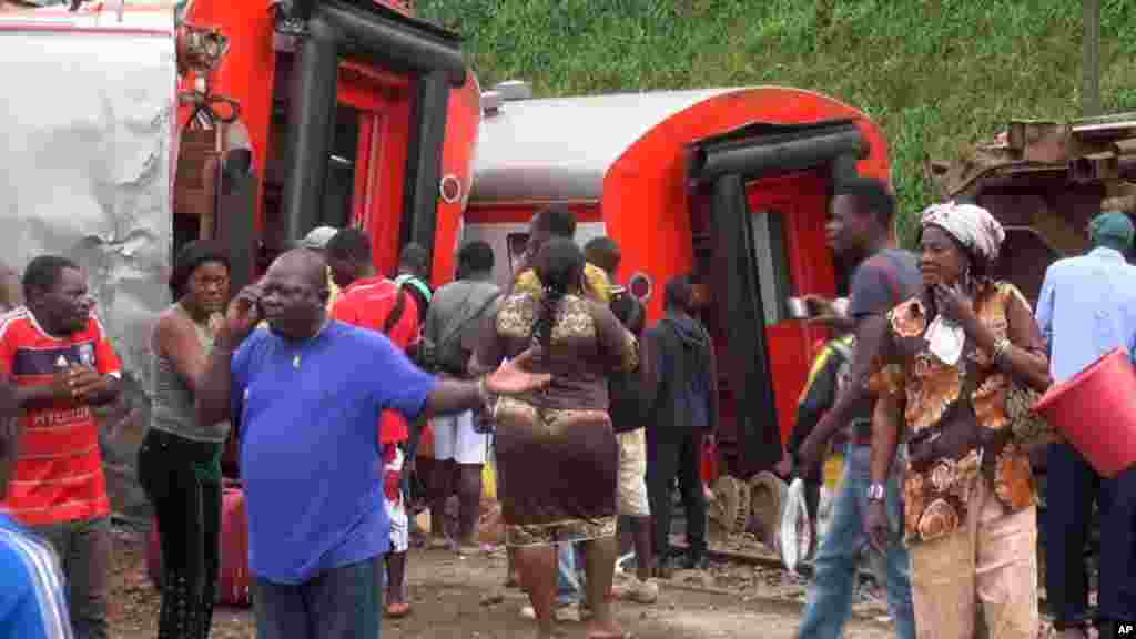 Les rescapés se tiennent à côté des wagons déraillés après l’accident d’un train a l’entrée de la gare Eseka, au Cameroun, 21 octobre 2016.