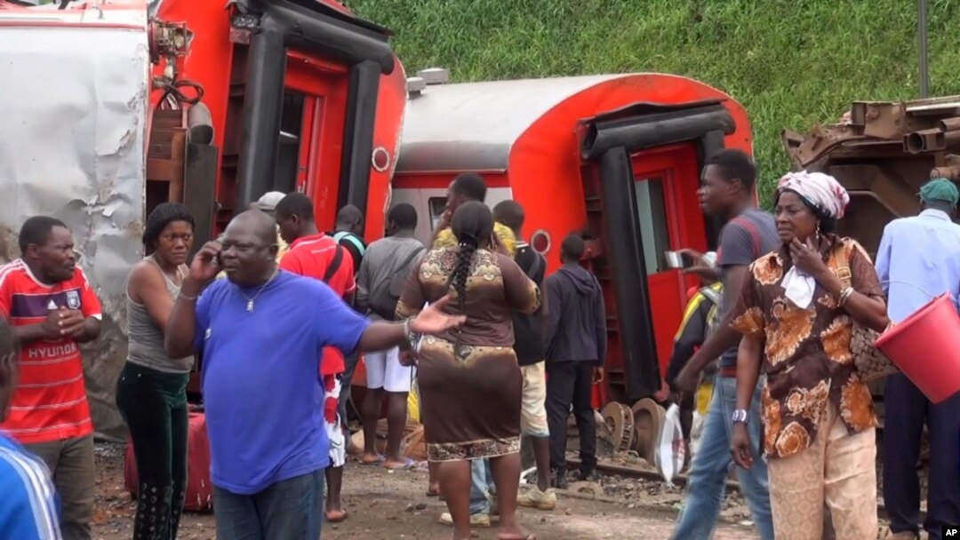 In this image made from video, passengers stand beside derailed train carriages after an accident in Eseka, Cameroon, Oct. 21, 2016.