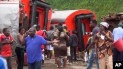 In this image made from video, passengers stand beside derailed train carriages after an accident in Eseka, Cameroon, Oct. 21, 2016.