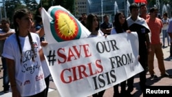 FILE - Women hold a banner during a demonstration marking the first anniversary of Islamic State's surge on Yazidis of the town of Sinjar, in front of the United Nations European headquarters in Geneva, Switzerland, August 3, 2015.