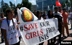 FILE - Women hold a banner during a demonstration marking the first anniversary of Islamic State's surge on Yazidis of the town of Sinjar, in front of the United Nations European headquarters in Geneva, Switzerland, Aug. 3, 2015.
