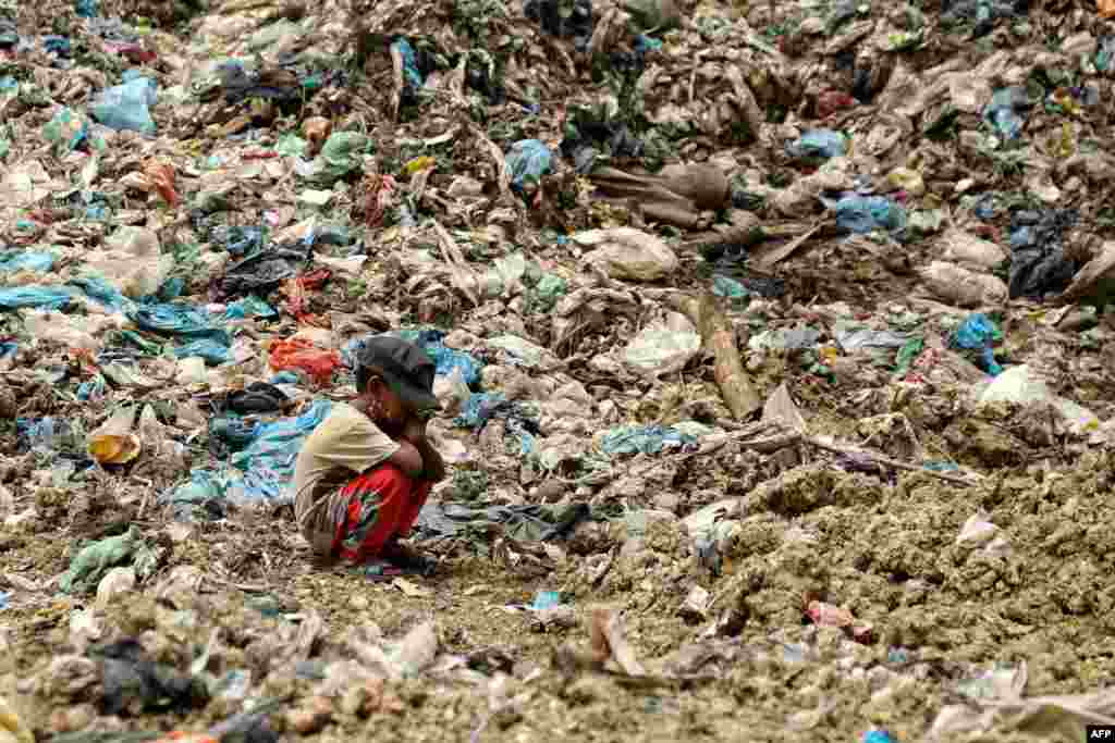 The son of a garbage collector rests as his father (not pictured) looks for items that can be resold, at a landfill site in Alue Liem in Lhokseumawe, Indonesia.