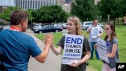 FILE - Claire Summers, 16, gets a high five as she and her sister Ella Summers, 10, protest the Southern Baptist Convention's treatment of women, outside the convention's 2018 meeting in Dallas.