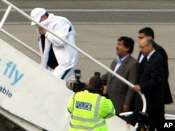 FILE - Lockerbie airline bomber Abdel Basset al-Megrahi, left, who was released from prison on compassionate grounds because he was terminally ill, boards an airplane accompanied by Libyan officials at Glasgow airport, Glasgow, Scotland, Aug. 20, 2009.