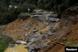 People look at a highway, that connects with the south of the country, collapsed by Tropical Storm Nate in Casa Mata, Costa Rica, Oct. 6, 2017.