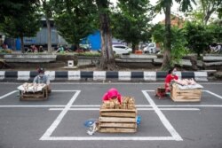 Para pedagang duduk di tempat yang disediakan di sebuah jalan di Surabaya untuk menjaga jarak aman agar terhindar dari penularan Covid-19, 2 Juni 2020. (Foto: AFP)