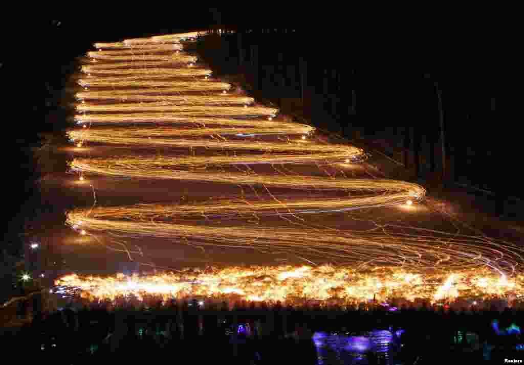 Hundreds of skiers and snowboarders hold lit torches and flashlights while descending from a slope during an annual festival in the Siberian town of Zheleznogorsk near Krasnoyarsk, Russia, March 3, 2018.