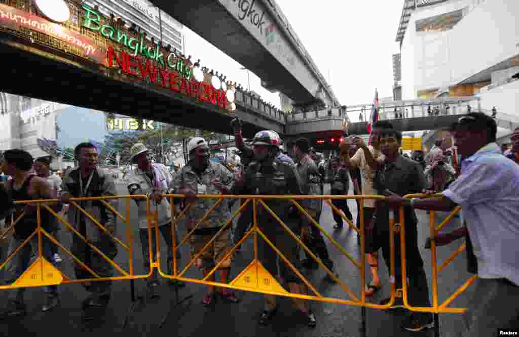 A traffic policeman talks to anti-government protesters as they set up barricades to close the roads at a major intersection, Bangkok, Thailand, Jan. 12, 2014.&nbsp;