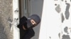 FILE - A masked policeman searches for clues at terrorist Mohamed Merah's apartment building in Toulouse, southern France. 