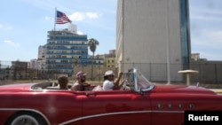 Tourists ride in a vintage car in front of the U.S. Embassy in Havana, Cuba, March 17, 2016.