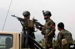 FILE - Afghan military soldiers stand stand alert at the entrance gate of the new parliament building after a rocket attack in Kabul, Afghanistan.