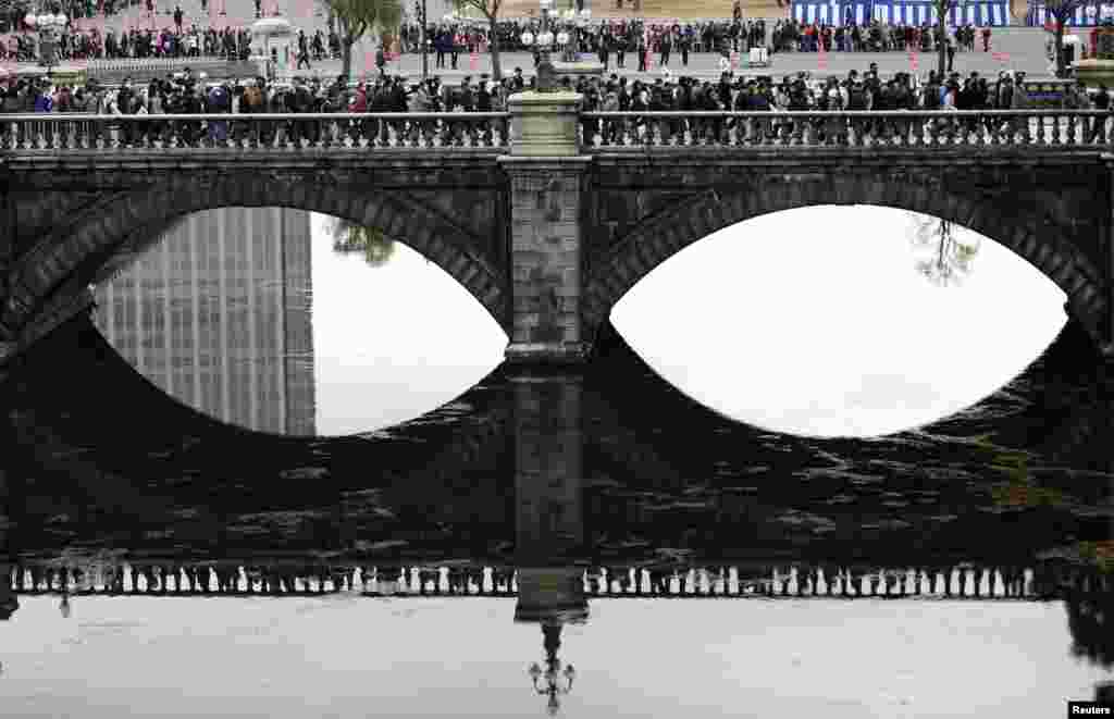 Well-wishers cross a bridge outside the Imperial Palace as they make their way to attend an event to celebrate Japan&#39;s Emperor Akihito&#39;s 80th birthday at the Imperial Palace in Tokyo.