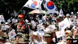 S. Korean war veterans wave their national flags during a rally denouncing N. Korea's nuclear program and former S. Korean president Kim Dae-jung's sunshine policy of engaging the North Korea, in Seoul, S. Korea, June 24, 2009. 