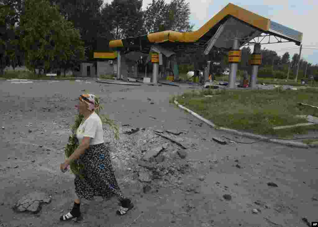 A woman walks past a gas station damaged by a mortar attack by Ukrainian government troops in Slovyansk, eastern Ukraine, June 9, 2014.