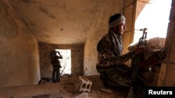 FILE - Kurdish People's Protection Units (YPG) fighters take up positions inside a damaged building in the al-Vilat al-Homor neighborhood in Hasaka, Syria, July 22, 2015.