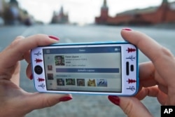 A user of Russia’s leading social network internet site VKontakte, poses holding an iPhone showing the account page of Pavel Durov, the former CEO and founder of VKontakte, in Red Square in Moscow, April 23, 2014.