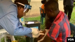 Seorang petugas kesehatan memberikan vaksin ebola di distrik Kasese, Uganda, Minggu (16/6). (Foto: H. Athumani/VOA)