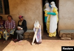 Health care workers enter a house where a baby suspected of dying of Ebola is, during the funeral in Beni, North Kivu Province of Democratic Republic of Congo, Dec. 18, 2018.